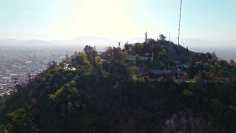 Vista-Aérea-Panorámica-De-La-Cima-Del-Cerro-San-Cristobal-Con-La-Estatua-De-La-Virgen-María-En-La-Cima,-Santiago,-Chile