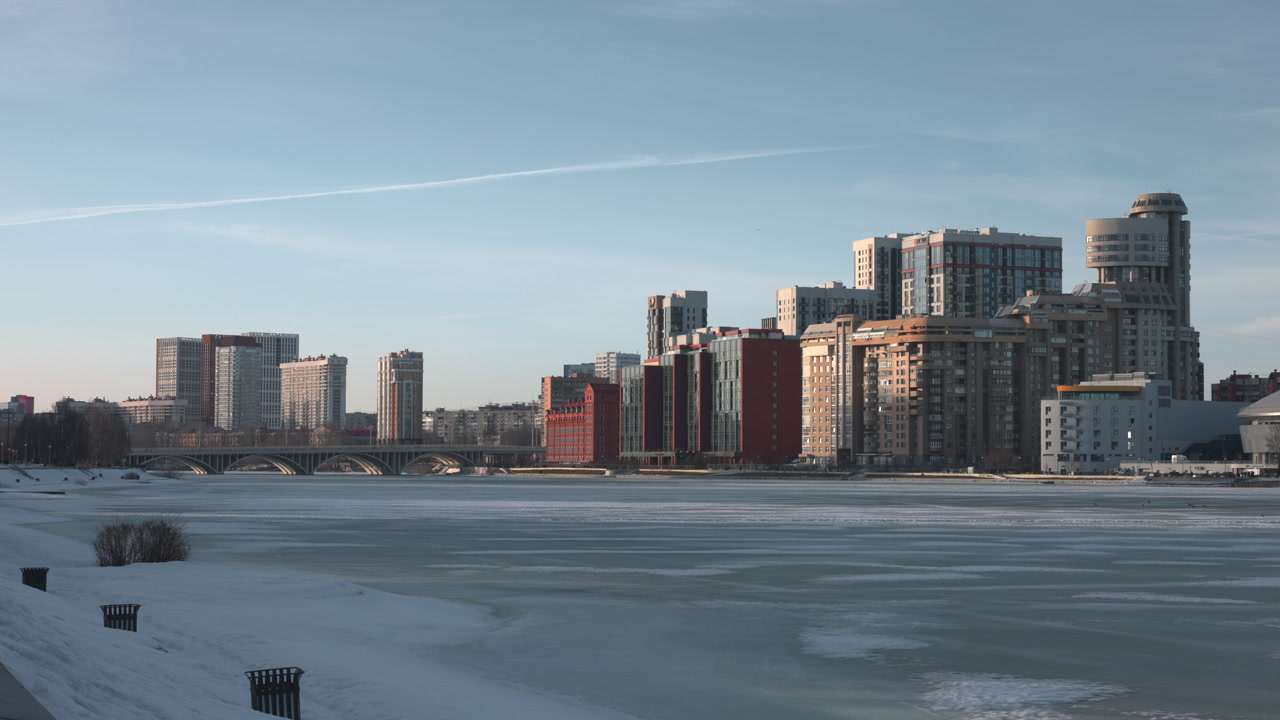 Dusk Urban Park With Snow, Solitary Walker Crosses Path Near Birch Trees, Highrise Skyline Glowing, Melting . Media