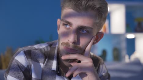 Thoughtful-young-man-at-home-alone-looking-away.