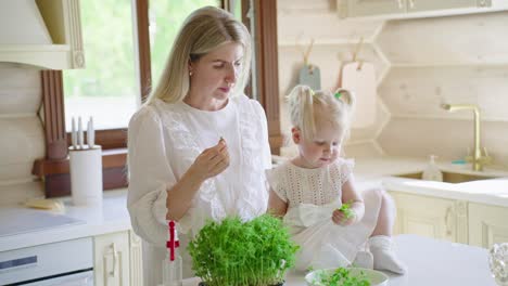 mother and daughter eating microgreens in the kitchen