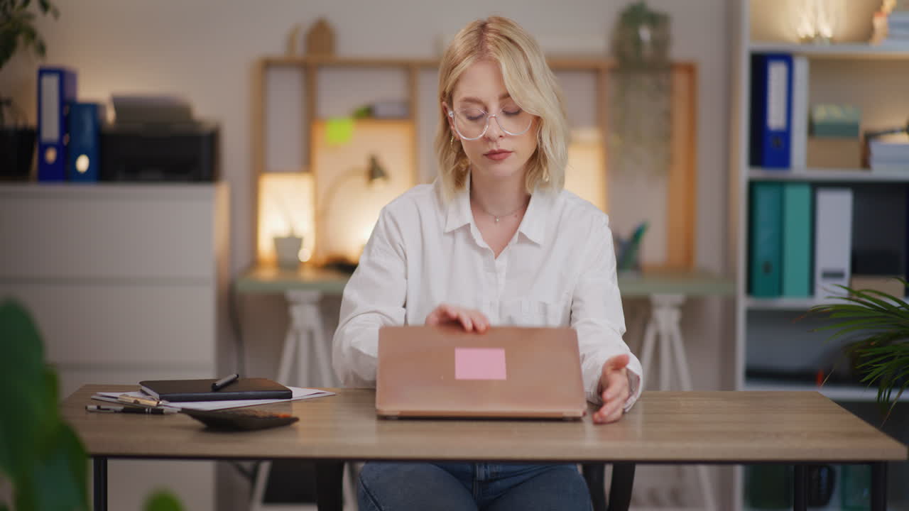 Donna apre il laptop di sera per recuperare il lavoro