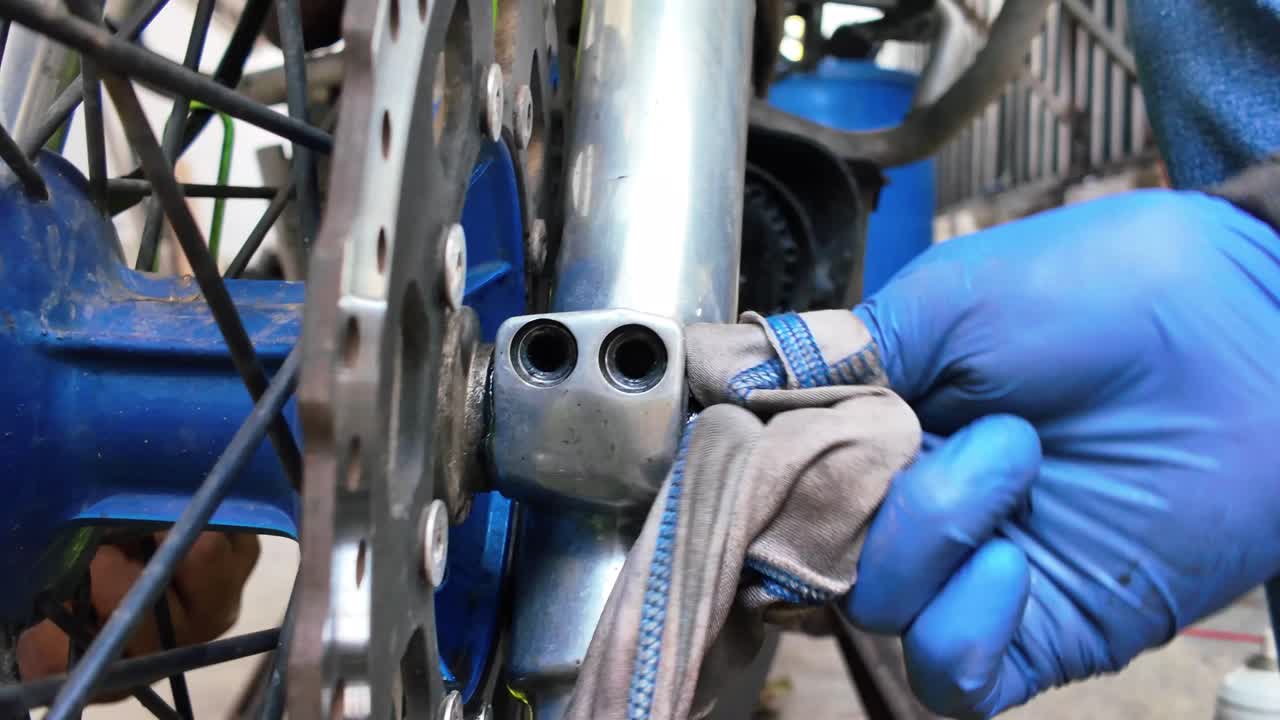 Close-up de homens ajustando a suspensão da roda dianteira de uma motocicleta