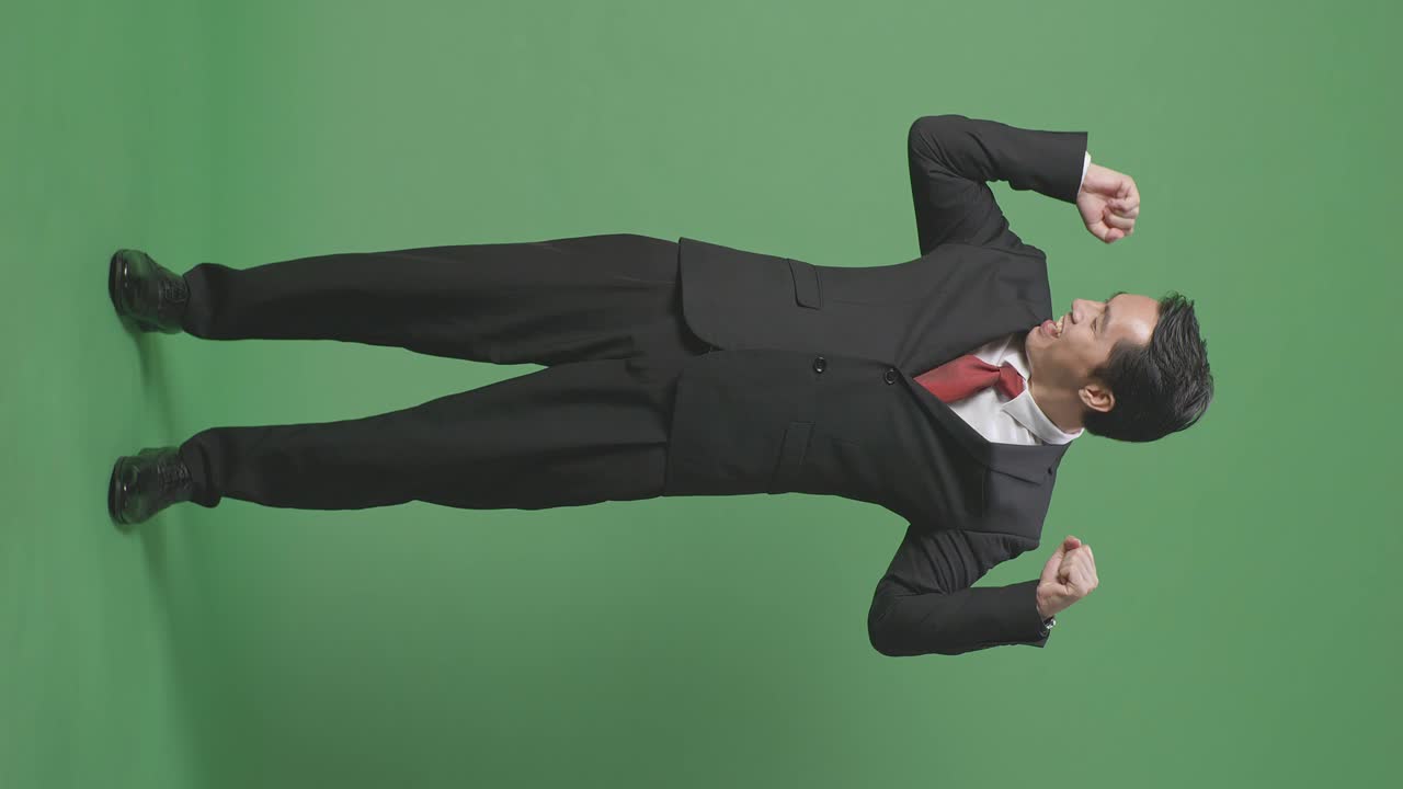 아시안 사업가의 몸이 가득한 미소와 근육을 녹색 스크린 배경에서 스튜디오에서 구부립니다.