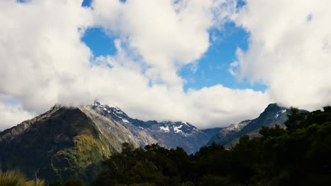 el lapso de tiempo de las nubes que pasan sobre montañas boscosas con picos cubiertos de nieve