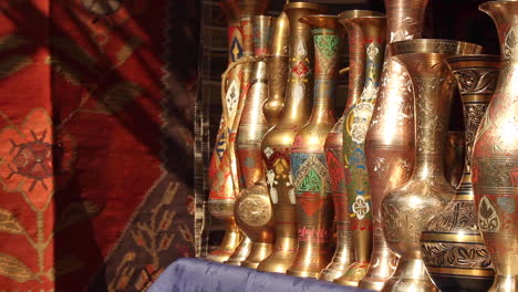 seleção de vasos banhados a ouro ornamentados alinhados em uma fileira no mercado ao lado de tapete feito à mão em yerevan, armênia