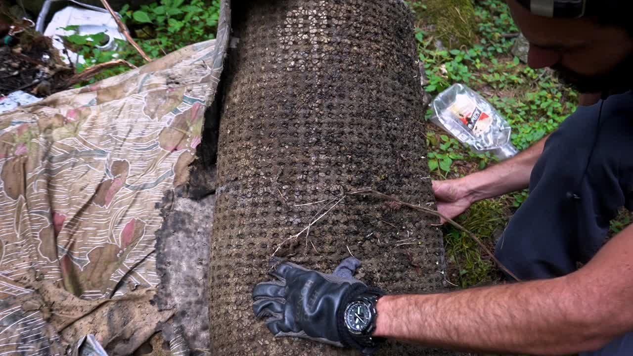 un voluntario tirando un viejo colchón sucio en el bosque en manali, himachal pradesh, india - toma panorámica