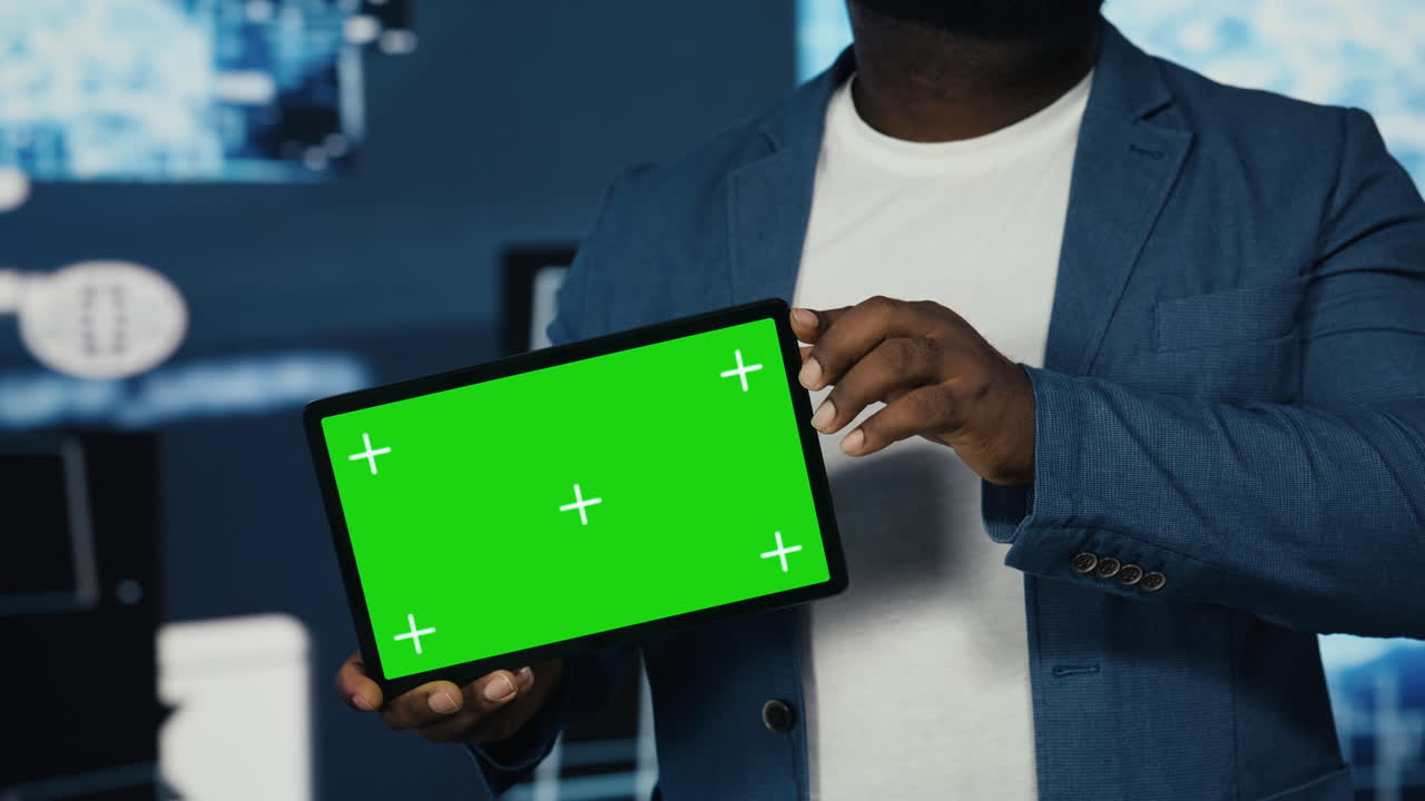 Young technician holding a tablet with chroma key next to AI coding interfaces