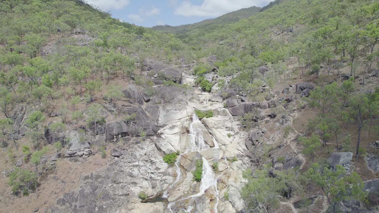 emerald creek cae con agua cayendo en cascada por rocas de granito en mareeba, australia - retroceso aéreo