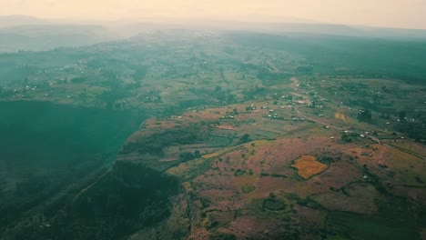 drone captures cultivated plots and scattered homes along the cliffs of mount elgon in kapchorwa, uganda, with expansive views of the fertile landscape under soft daylight