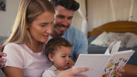 Familie-Sitzt-Zu-Hause-Auf-Dem-Sofa,-Eltern-Lesen-Buch-Mit-Kleinem-Sohn