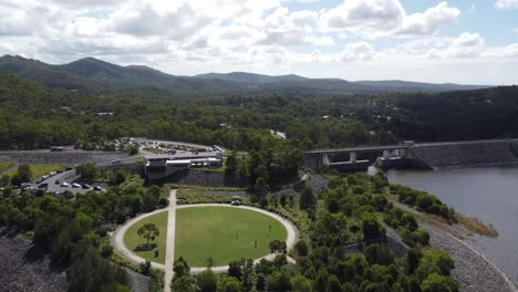 flying over a green field near a dam wall