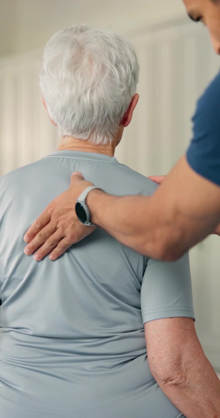 Physical Therapist Examining Senior Woman's Back in Clinic