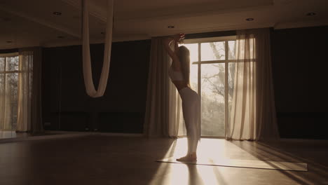 lens flare :a young woman in white sportswear is stretching with a large hall with large windows in a slow-motion scheme the sun's rays shine through the window. healthy lifestyle healthy morning