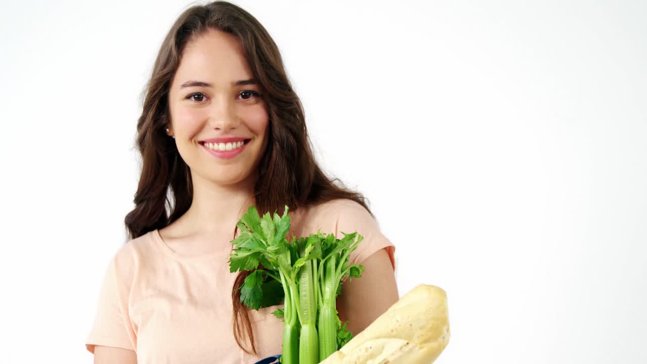 Retrato de mujer sonriente sosteniendo una bolsa de supermercado