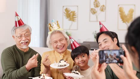 a joyful family captures a birthday moment with cake, smiles, and selfies in a warmly lit room