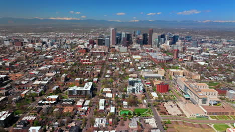 downtown denver colorado rhino city park cityscape vibrant spring summer aerial drone sunny blue sky snow capped rocky mountains front range green lush grass trees blossom forward motion