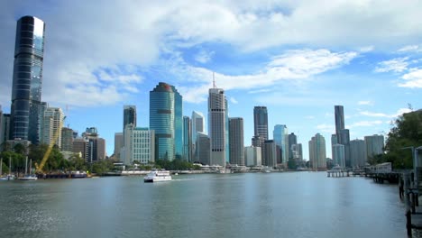 classic view of central brisbane from across the river, with the sun accenting the modern city highrises as a river ferry sails through the foreground