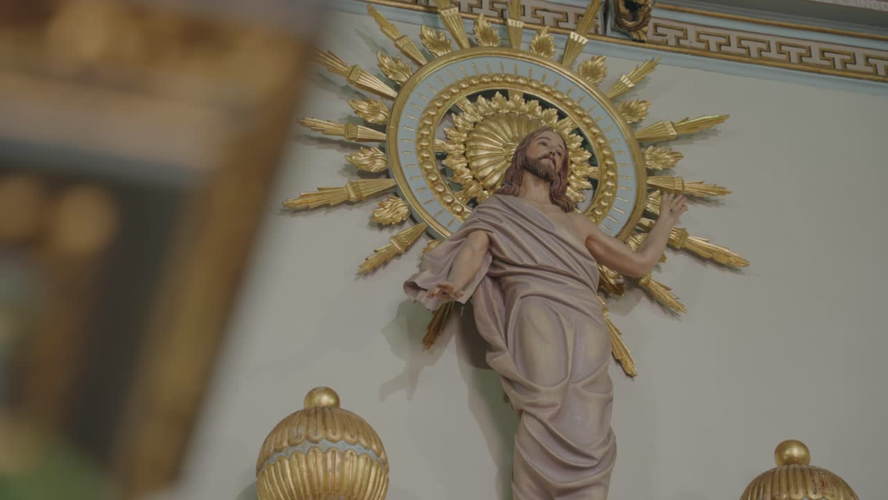 Close-up of statue of Jesus Christ with radiant golden halo detail inside ornate church interior