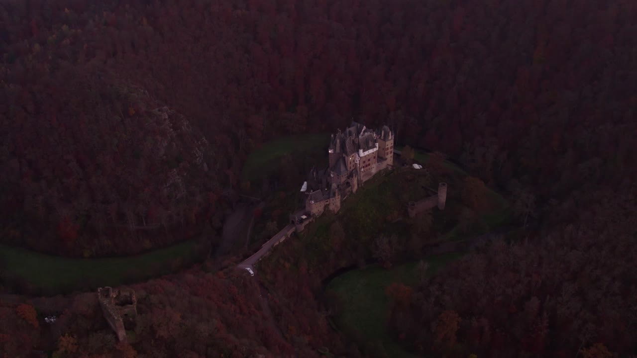 Historic Burg Eltz surrounded by wooded hills in evening light, Germany