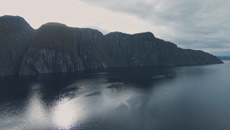 vast lake and majestic rocky mountain range with sunshine, aerial drone view