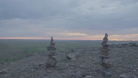 sunrise over a mountain range with rock cairns