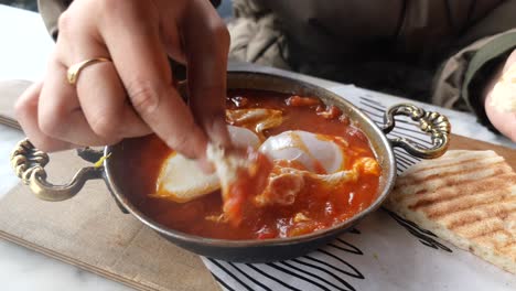 mujer comiendo shakshuka con pan