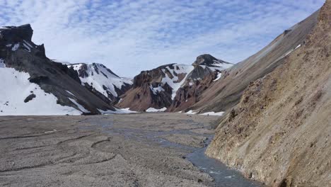 Aufsteigender-Drohnenblick-über-Die-Rhyolithberge-Von-Landmannalaugar-Im-Brandsgil-Tal,-Der-Sommerlandschaften-Mit-Schneeresten-Zeigt