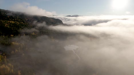 Frosty-autumn-morning-flying-above-the-clouds,-in-the-gaps-between-the-clouds-you-can-glimpse-the-landscape