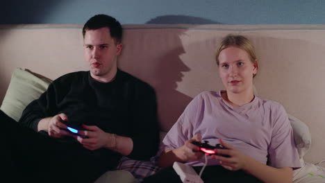 young couple playing video games in bed at night