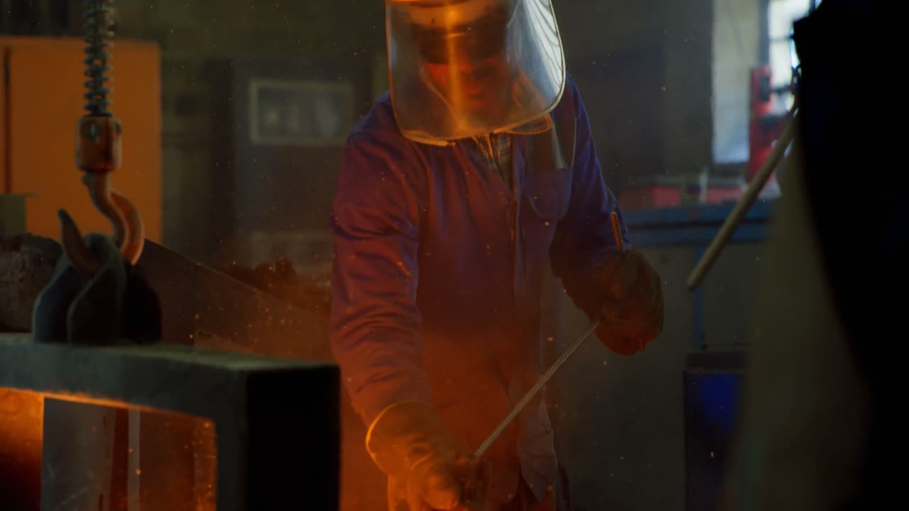 Male worker putting molted metal in furnace at workshop 4k