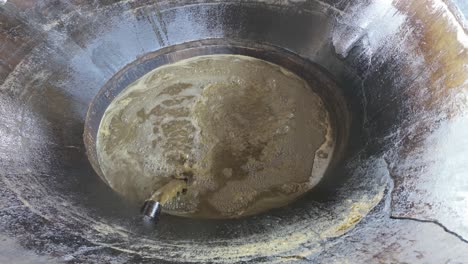 process of making jaggery: sugarcane syrup bubbling in a rustic pot