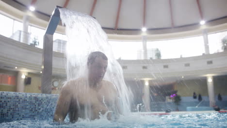 Hombre-Bajo-El-Chorro-De-Agua-En-La-Piscina