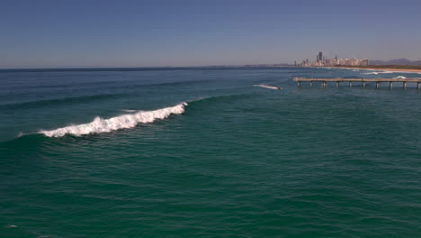 Luftaufnahme-Der-Wellen,-Die-Sich-An-Einem-Schönen-Tag-Brechen,-Mit-Blick-Auf-Die-Beliebte-Stadt-Surface-Paradise-Im-Hintergrund-An-Der-Spit-Gold-Coast-QLD-Australien