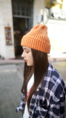 woman wearing orange knitted hat in city street