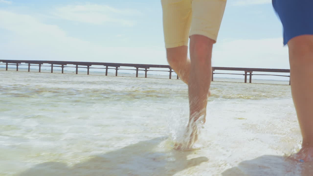 Barefoot couple running in shallow water on the beach