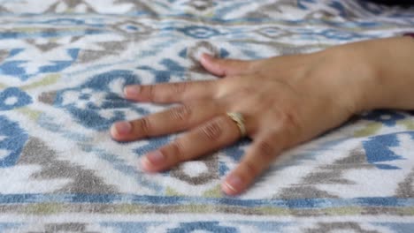 woman's hand with ring on a patterned blanket