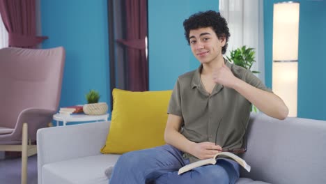 Smiling-boy-looking-at-camera-while-reading-a-book.