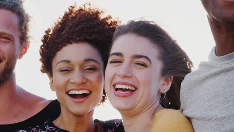cabeza y hombros retrato de amigos jóvenes sonrientes al aire libre juntos contra el sol abrasador