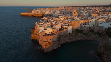 sunset light at polignano a mare, apulia, italy. old town on cliffs, seafront, rocky coastline.