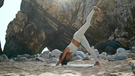 donna che fa una postura verso il basso praticando yoga sulla sabbia spiaggia di ursa orientata verticalmente