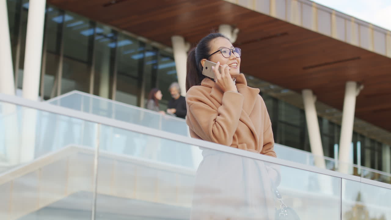 Young Woman Talking on Smartphone Outdoors in a Modern Setting