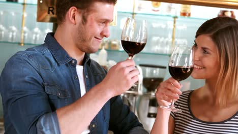 una pareja brindando por una copa de vino.