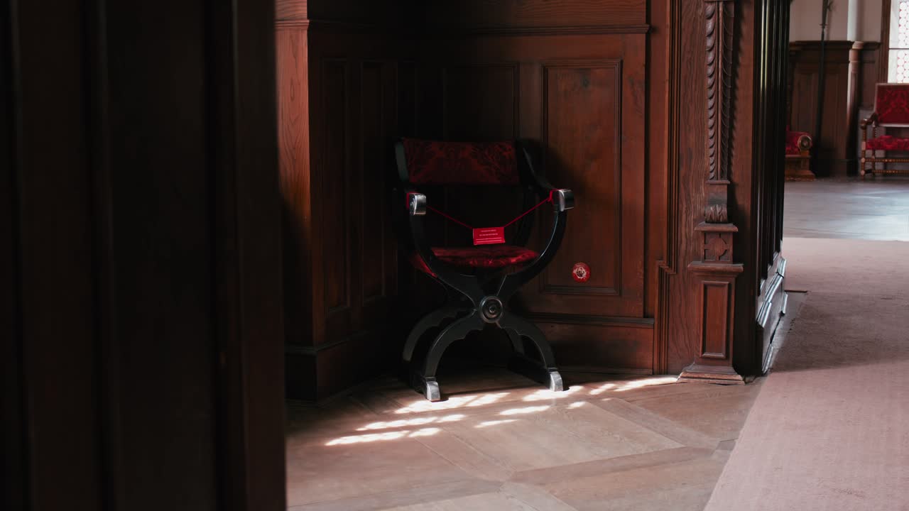 одинокий красный бархатный стул в спокойной библиотеке замка тракощан, освещенный солнечным светом