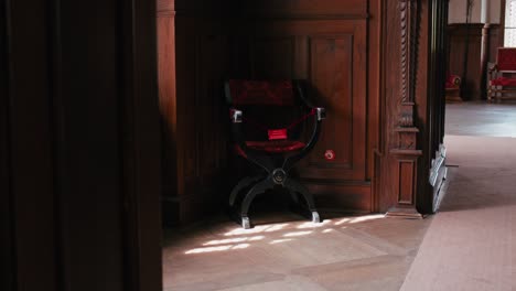 silla de terciopelo rojo solitaria en la tranquila biblioteca del castillo de trakošćan, iluminada por la luz del sol
