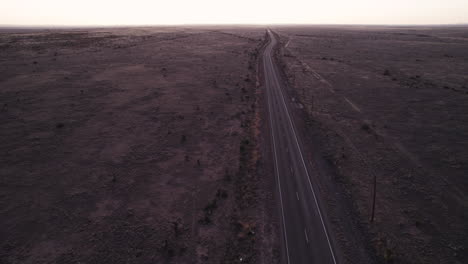 sunset drone shot of a vehicle driving down a remote desert highway