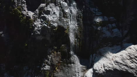 aerial view of fast flowing narrow mountain waterfall in fiordland southland, new zealand