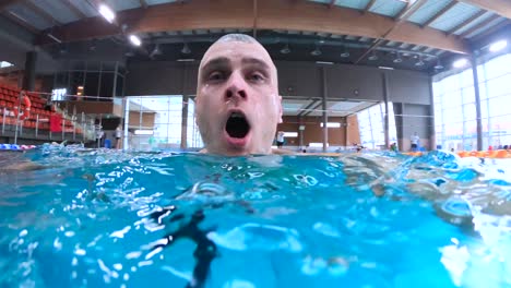 man swimming submerging underwater in public swimming pool