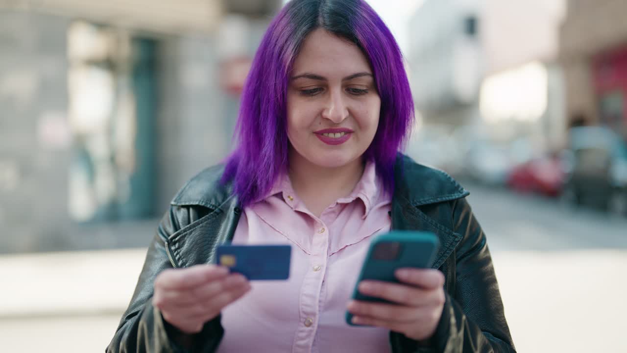 mujer joven de tamaño plus usando teléfono inteligente y tarjeta de crédito en la calle