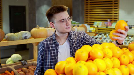 man shopping for oranges at a grocery store