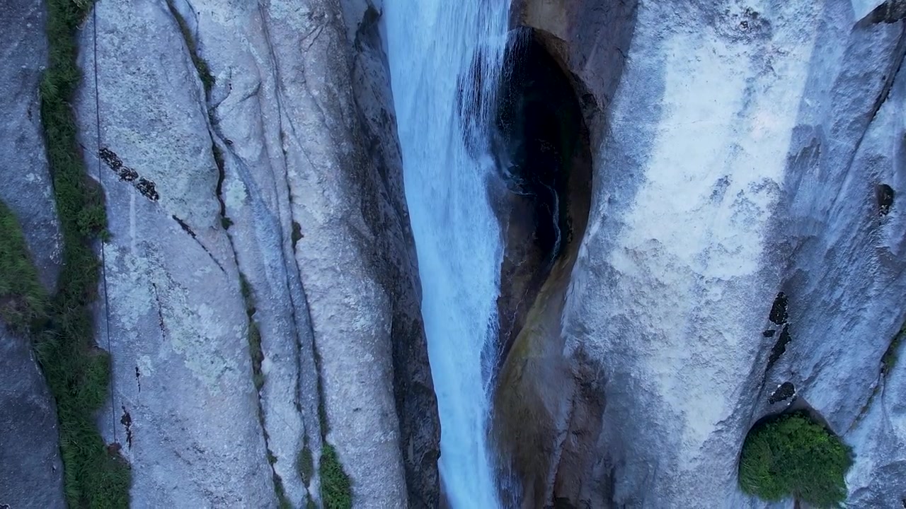 Primo piano di una potente cascata che si precipita attraverso una stretta gola rocciosa con pareti di scogliera lisce
